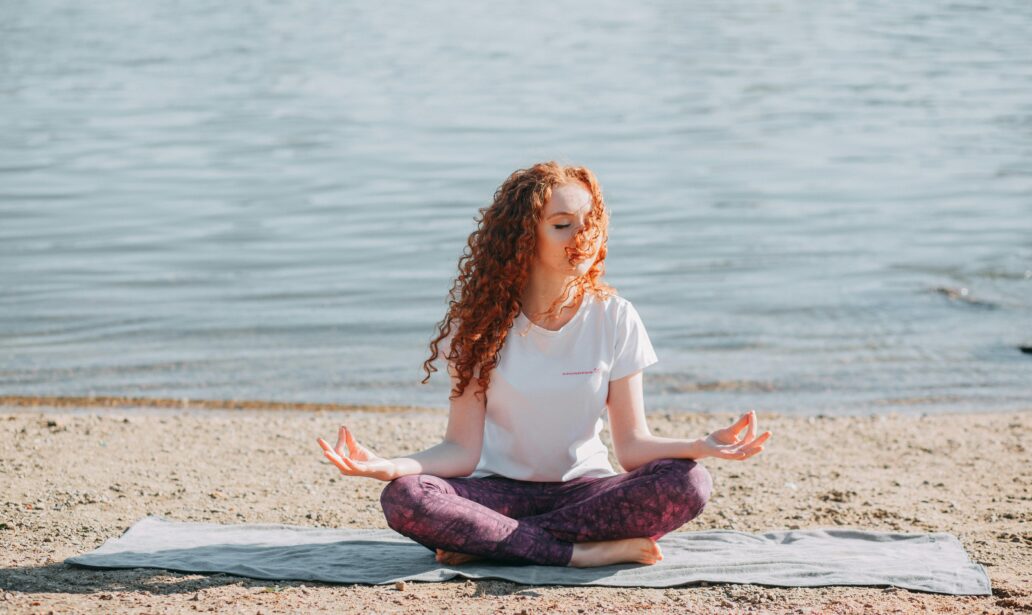 a woman meditating near an ocean