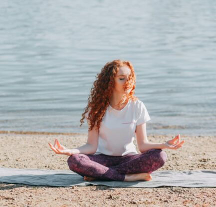 a woman meditating near an ocean